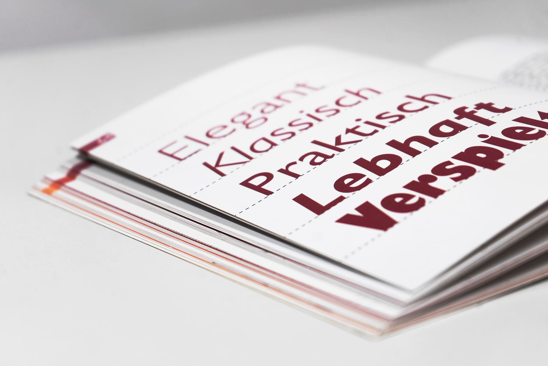 Aufgeschlagenes Buch. Auf der Seite 5 Wörter in Rot "Elegant" (dünne Schrift), "Klassisch", "Praktisch", "Lebhaft" (dickere Schrift), "Verspielt" (fette Schrift)
