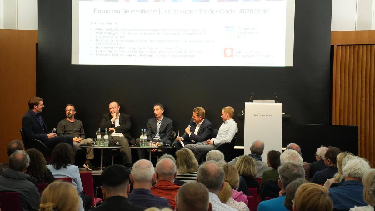 Öffentliche Podiumsdiskussion im Fritz-Thyssen-Haus unter der Fragestellung „Fluch oder Segen? KI in Wirtschaft, Wissenschaft und Gesellschaft“, bei der Vertreter:innen aus Forschung, Wirtschaft und Studierende über die Auswirkungen von KI diskutierten.